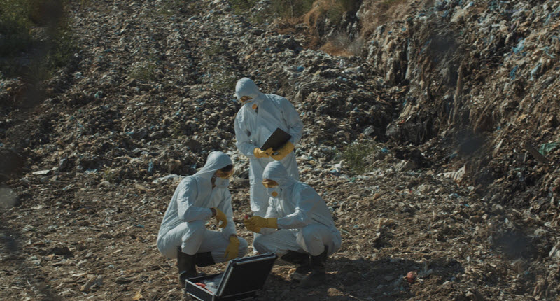 Team of ecology experts examining soil pollution on dirty landfill site